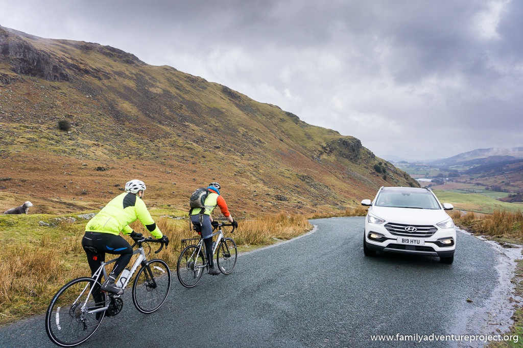 Hyundai Santa Fe passing descending cyclists as it climbs to the summit of the Wrynose Pass