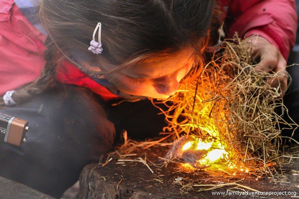 Girl lighting fire on Bear Grylls Survival Academy Course
