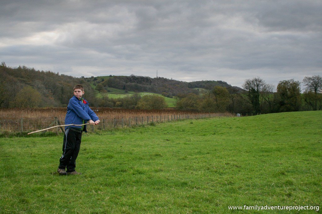 Boy wields a stick in Cumbrian landscape